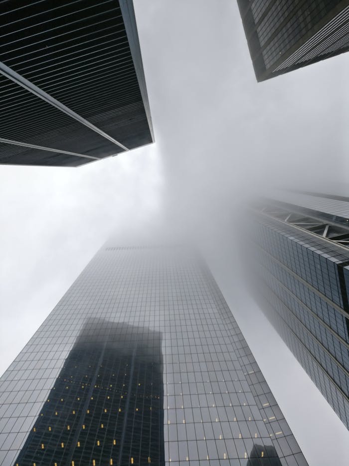 Dramatic view of skyscrapers disappearing into fog in New York City, showcasing urban architecture.